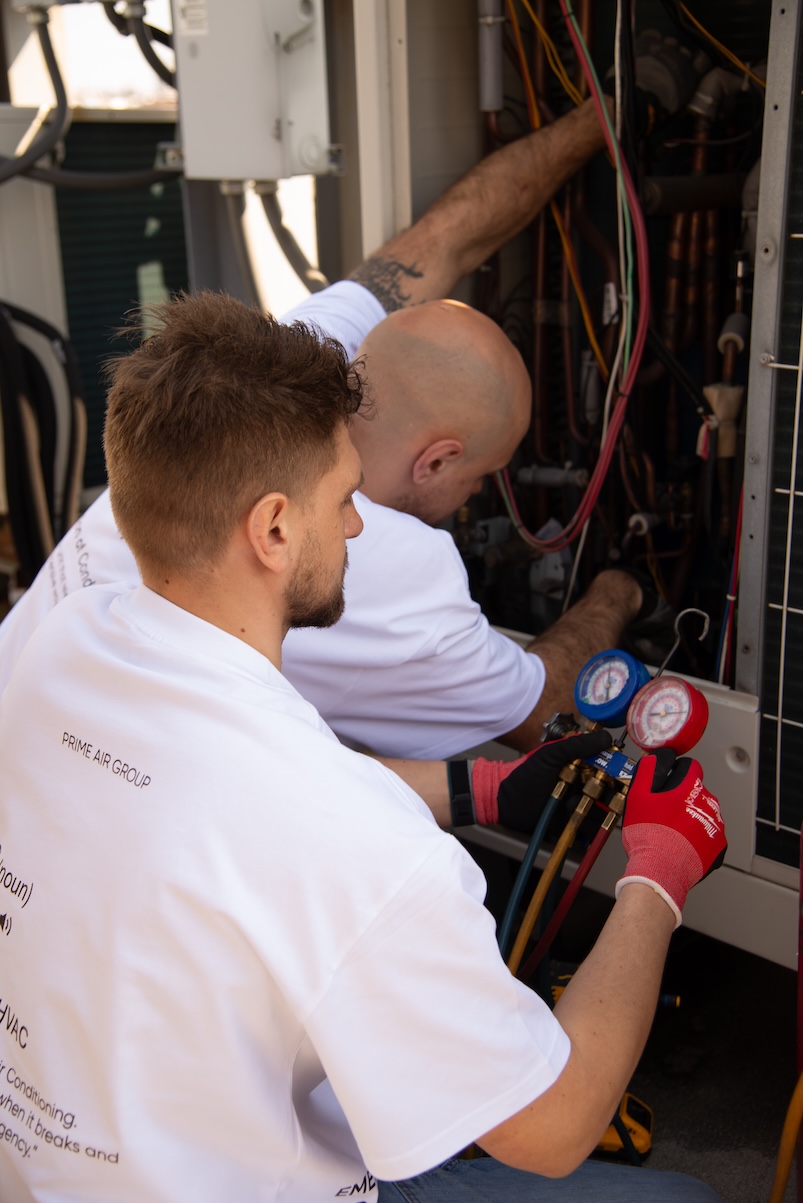 Two Prime Air Group technicians servicing the same HVAC unit