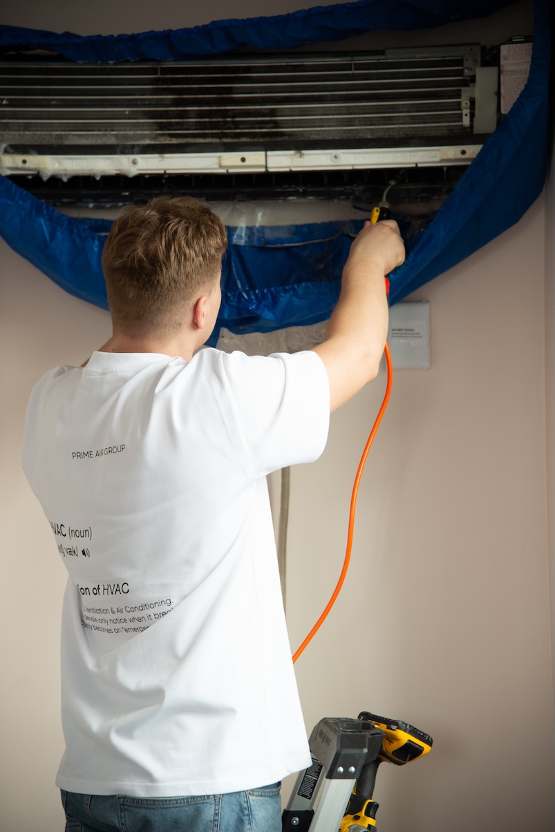Technician deep-cleaning a wall-mounted AC unit